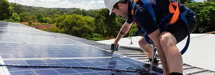 Technician Performing Solar Panel Installations on a Rooftop